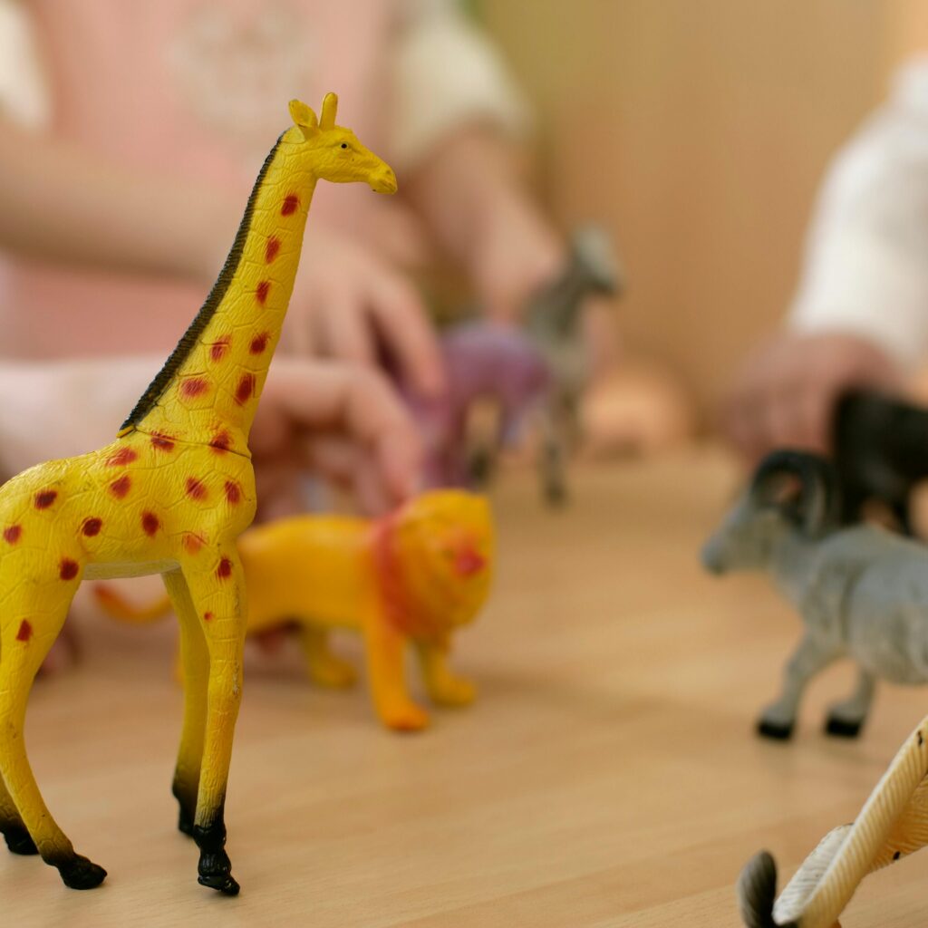 Close-up of children's hands playing with animal plastic toys.