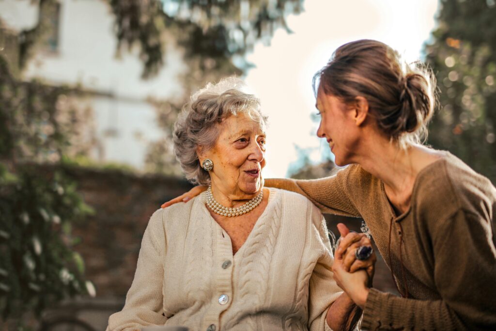 pexels photo 3768131 3768131 Elderly woman and adult daughter share a joyful, affectionate moment in a sunny garden.