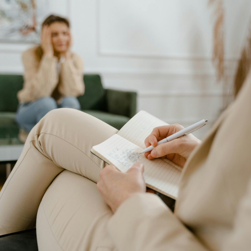 A therapist taking notes during a consultation with a patient, focusing on mental health.